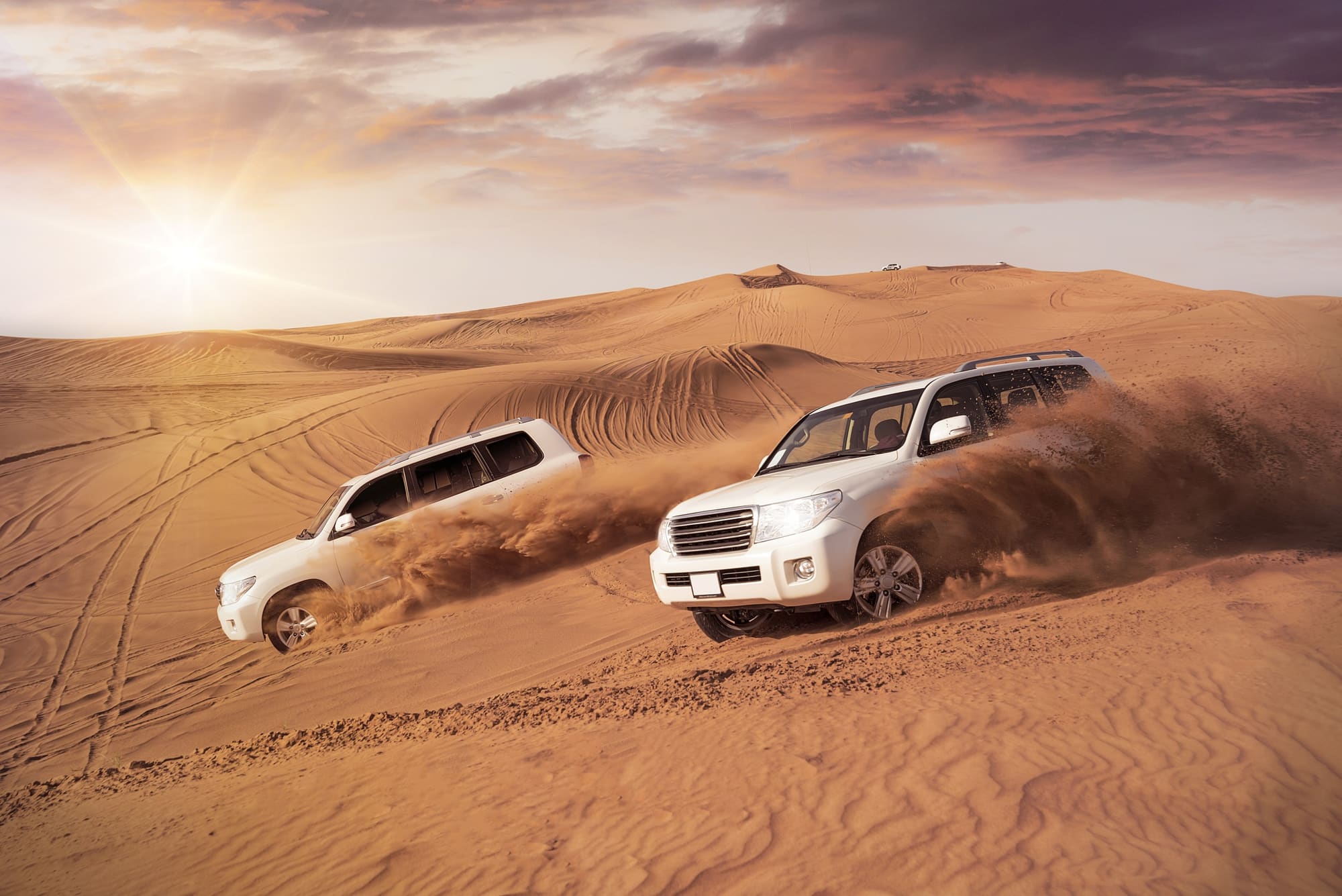 A four-wheel-drive cresting a red dune on a Dubai desert safari