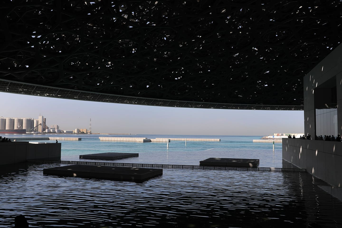 The perforated dome of Louvre Abu Dhabi casting dappled light over the water